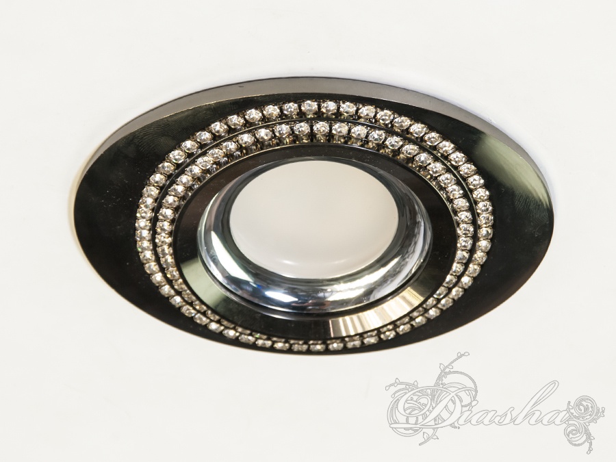 Металевий точковий світильник, є частиною нової серії врізних точкових світильників. Цей предмет може здатися на перший погляд незвичайним і вражає своїми формами. Його дизайн поєднує в собі елементи мінімалізму та декоративності: гладка, блискуча чорна металева поверхня контрастує з яскравими кристалами, інкрустованими по обід внутрішньої частини світильника. Ці кристали додають розкоші та вишуканості, і в той же час є ненав'язливими, підкреслюючи сучасний стиль інтер'єру.
Світильник призначений для врізного монтажу в отвір діаметром 6 см, що робить його універсальним варіантом для більшості стандартних врізних систем освітлення. Максимальна потужність лампи для цього світильника становить 50 Вт, що дозволяє використовувати його для створення як м'якого, так і досить яскравого світла в залежності від потреб простору.
Тип лампи, яку можна використовувати з цим світильником, може бути як галогеновою, так і світлодіодною (LED). Останній варіант є більш привабливим з точки зору енергоефективності та безпеки, оскільки LED-лампи споживають менше електроенергії та виділяють менше тепла.
Світильники, призначені для ламп типу MR-16, є одними з найпопулярніших на ринку завдяки легкості установки лампи та великій різноманітності вибору дизайну. Цей тип світильників може використовуватися в різних приміщеннях, починаючи від житлових кімнат та закінчуючи офісними просторами або комерційними виставковими залами.
Загальний вигляд цього світильника від ТМ &laquo;Даіша&raquo; свідчить про його високу якість та дизайнерську привабливість, що дозволяє йому гармонійно вписуватися в сучасні дизайни інтер'єрів, доповнюючи їх і створюючи в просторі відчуття завершеності та стилю.
Для оптових покупців відпускається тільки ящиками по 50шт.
Лампа і трансформатор в комплект не входять.