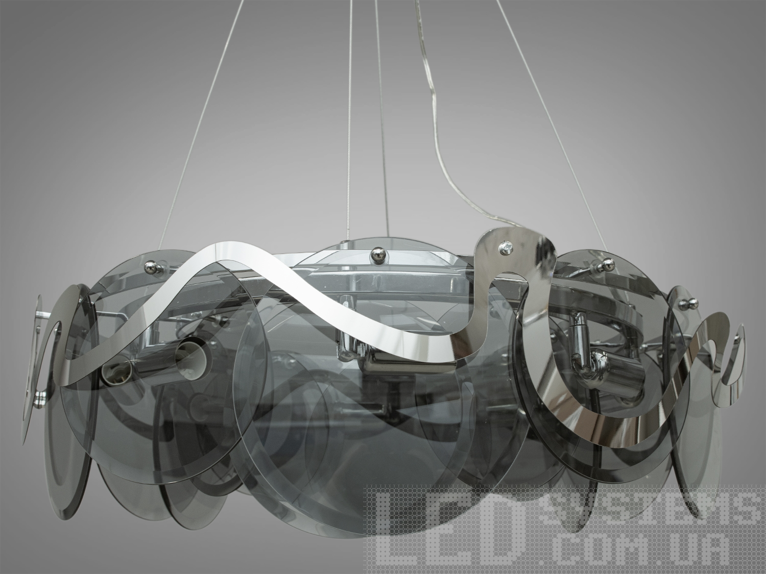 Сучасна люстра-підвіс з круглими скляними елементами на 8 ламп, з металевим корпусом добре виглядатиме в сучасному інтер'єрі зали, спальні, коридору або кухні.&nbsp;На неї можна дивитися під будь-яким кутом, і не дивлячись на легкість конструкції люстри, ви завжди бачитимете лампи тільки через димчасте скло.&nbsp;Висота люстри регулюється, завдяки чому підходить для низьких стель. Люстра-підвіс під звичайні лампочки розжарювання, економки або світлодіодні лампи з цоколем Е14.&nbsp;Стельове кріплення на планку універсальне підходить для навісних, натяжних та звичайних стель.&nbsp;
Увага. Вага люстри понад 10 кг.
Лампи в комплект не входять.
&nbsp;