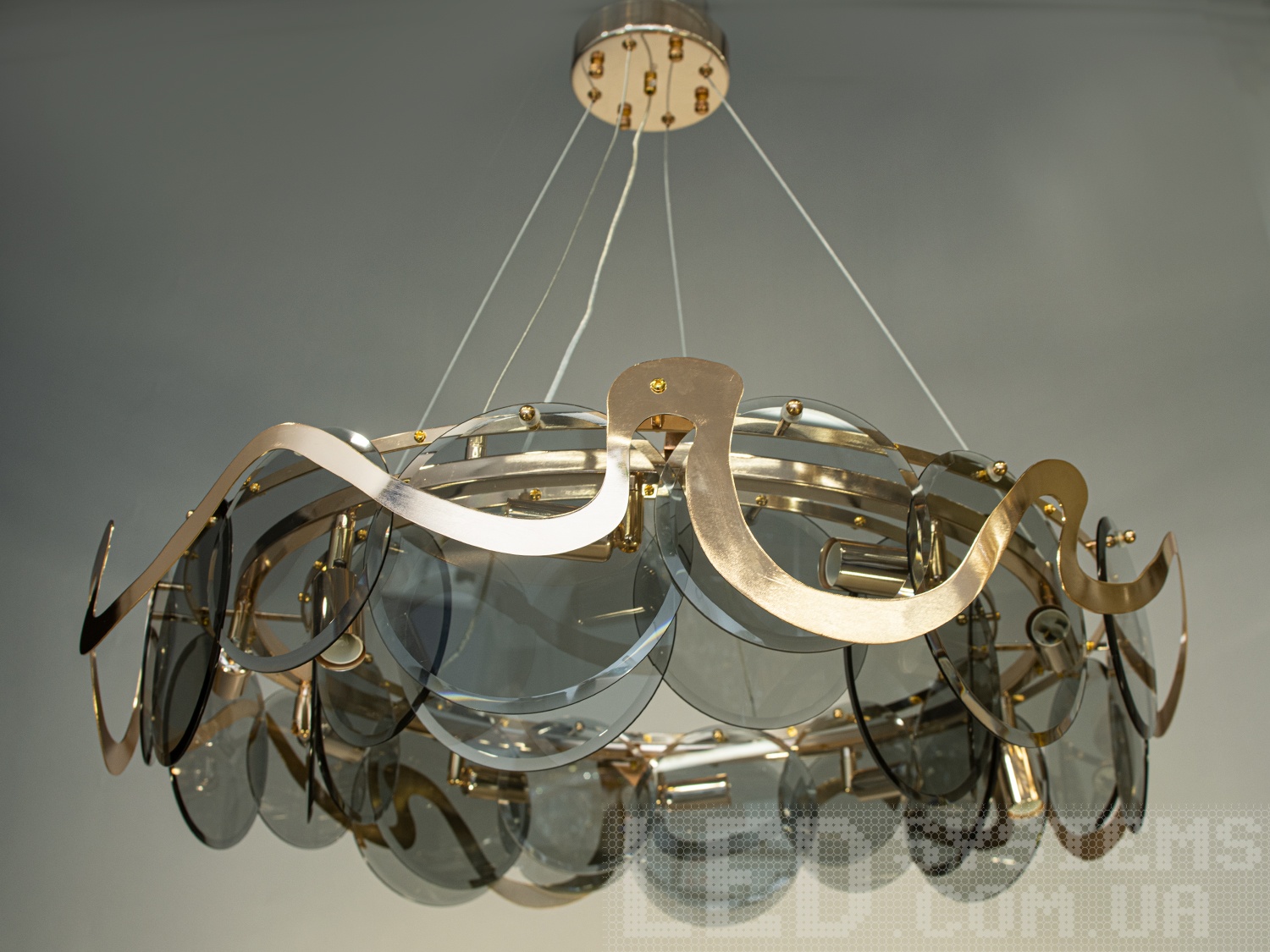 Люстра підвіс із круглими скляними елементами, з металевим корпусом добре виглядатиме в сучасному інтер'єрі зали, спальні, коридору або кухні. На неї можна дивитися під будь-яким кутом, і не дивлячись на легкість конструкції люстри, ви завжди бачитимете лампи тільки через димчасте скло. Висота люстри регулюється, завдяки чому підходить для низьких стель. Стельове кріплення на планку універсальне підходить для навісних, натяжних та звичайних стель.
Увага. Вага люстри понад 10кг.
&nbsp;