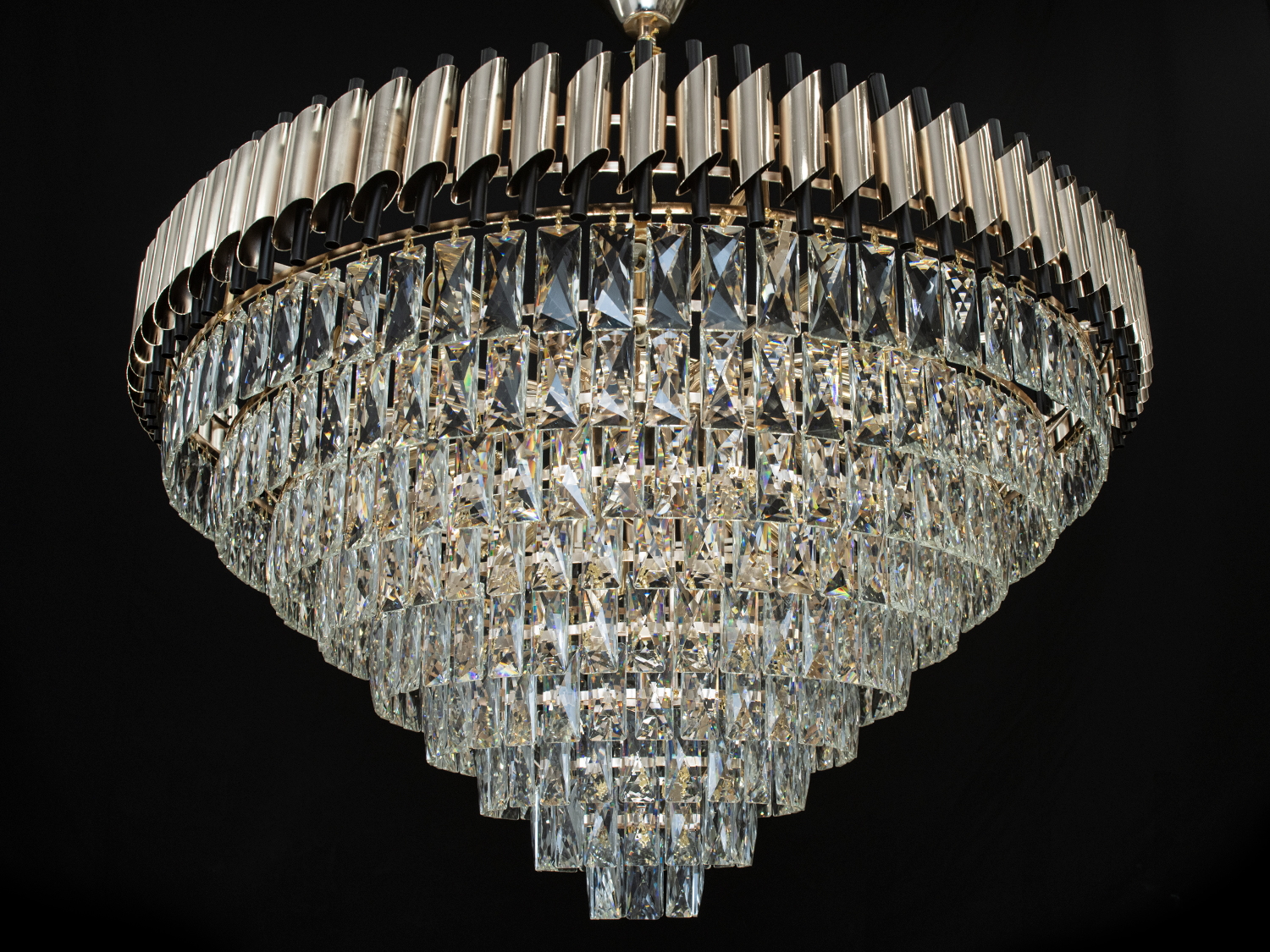 Сучасна кришталева люстра для залу з металевим корпусом добре виглядатиме в інтер'єрі зали, вітальні, їдальні. У класичний інтер'єр вона вносить нотки сучасності та легкої грайливості, а квартирі студії в стилі лофт дарує крапельку строгості та впорядкованості. Висота люстри регулюється, завдяки чому підходить для низьких стель. Стельове кріплення на планку універсальне та підходить для навісних, натяжних та звичайних стель. Кришталева люстра-підвіска під звичайні лампочки з цоколем Е14.

Увага. Вага люстри 21.5кг.