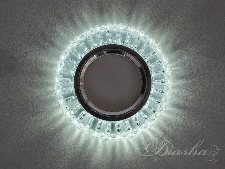 Зачаровуючий точковий світильник з LED підсвічуванням, розроблений ТМ &laquo;Діаша&raquo;. Цей точковий світильник врізний є не просто джерелом світла, а справжньою прикрасою інтер'єру, що здатна перетворити звичайне приміщення на витончений простір з неповторним атмосферним освітленням.
Серцем світильника є світлодіодна лампа MR16, що гарантує яскраве та чітке світло. Навколо лампи розташовано кільце з акрилової смоли, майстерно обробленої так, щоб імітувати блиск кристалів. Коли світильник увімкнений, кристали відбивають світло, створюючи ефект мерехтливих бенгальських вогнів або блискучих бризок Чорноморських хвиль.
Інноваційне особливість цього світильника полягає у його здатності змінювати колір підсвічування з холодного білого до рожевого, а також їхнього комбінування, що дозволяє створювати різноманітні настрої у просторі. Завдяки цій особливості світильник виходить за рамки традиційного освітлення та перетворюється на динамічний елемент дизайну.
Світлодіодне підсвічування потужністю 3 Вт при 4100К забезпечує ефективне та енергозберігаюче освітлення. Світильник легко інтегрується в будь-яку поверхню &mdash; гіпсокартон, дерево чи метал &mdash; і гармонічно вписується в натяжні стелі, що робить його відмінним рішенням для будь-якого сучасного простору.
Колекція світильників від &laquo;Діаша&raquo; пропонує широкий спектр моделей та кольорів, даючи змогу кожному знайти ідеальний варіант, який відповідає індивідуальним стильовим та функціональним вимогам. Чи потрібно освітлення для домашнього затишку або комерційного простору, цей світильник стане ключем до створення неповторної атмосфери з вишуканим блиском.
Лампа MR-16 та трансформатор у комплект не входять.