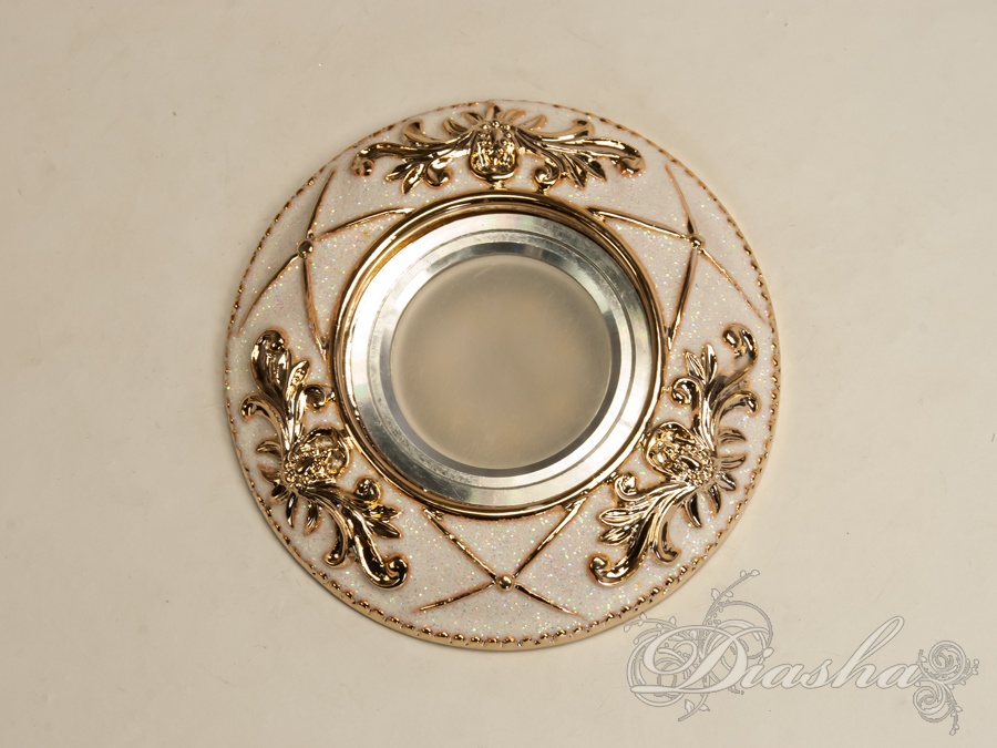 Гіпсовий точковий світильник є апофеозом класичного стилю та витонченої естетики. Він не просто виконує свою безпосередню функцію освітлення, але й слугує декоративним елементом, який здатен прикрасити і доповнити найвишуканіший інтер'єр.
Виготовлені з гіпсу, точкові світильники ідеально вписуються в класичну архітектуру приміщення, додаючи їй відчуття розкоші та історичної цінності. Їх можна гармонійно комбінувати з багетами та розетками під люстру, створюючи враження цілісності та продуманості кожної деталі.
Завдяки своїй універсальності, у цих світильниках можна використовувати як галогенові, так і світлодіодні лампи, які можуть бути підключені до мережі в 12 або 220 вольт. Світлодіодні лампи, зокрема, є найбільш енергоефективним вибором з великим терміном служби та мінімальним енергоспоживанням, що робить їх ідеальним рішенням для сучасного дому. При використанні ламп напругою 12В важливо не забувати про необхідність трансформатора, що забезпечить безпеку та стабільність роботи освітлювального приладу.
Зовнішній вигляд світильника з гіпсу вражає своєю ретельною обробкою та декоративними деталями. Витончені рослинні мотиви та золоті акценти на білому фоні створюють ефект аристократичної розкоші, підкреслюючи статусність інтер'єру та його власників. Це виріб не лише освітлює, а й привносить в будинок атмосферу величі та вишуканості.
Лампа в комплект не входить.