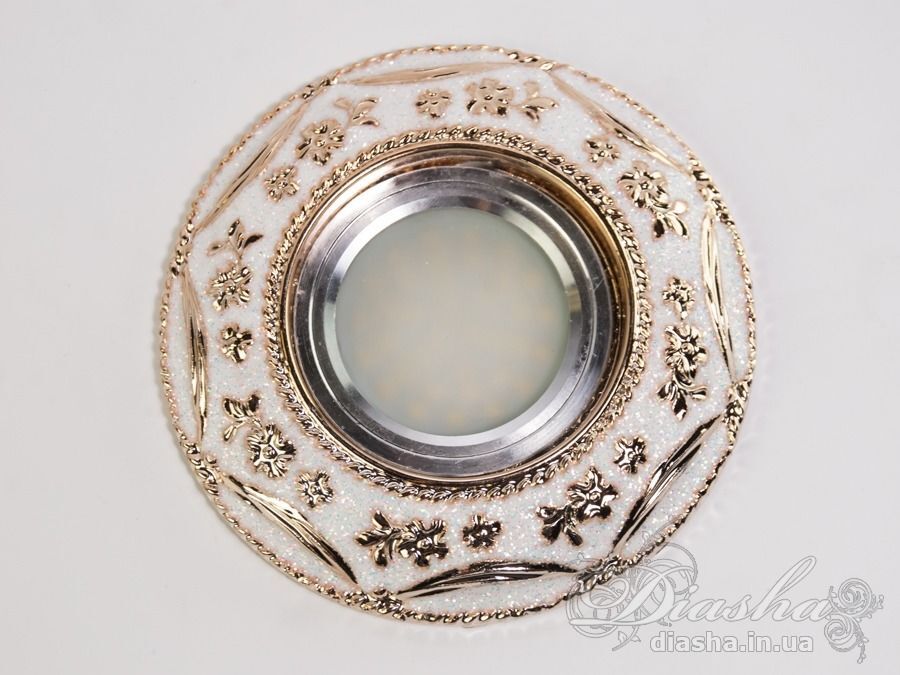 Гіпсовий точковий світильник є апофеозом класичного стилю та витонченої естетики. Він не просто виконує свою безпосередню функцію освітлення, але й слугує декоративним елементом, який здатен прикрасити і доповнити найвишуканіший інтер'єр.
Виготовлені з гіпсу, точкові світильники ідеально вписуються в класичну архітектуру приміщення, додаючи їй відчуття розкоші та історичної цінності. Їх можна гармонійно комбінувати з багетами та розетками під люстру, створюючи враження цілісності та продуманості кожної деталі.
Завдяки своїй універсальності, у цих світильниках можна використовувати як галогенові, так і світлодіодні лампи, які можуть бути підключені до мережі в 12 або 220 вольт. Світлодіодні лампи, зокрема, є найбільш енергоефективним вибором з великим терміном служби та мінімальним енергоспоживанням, що робить їх ідеальним рішенням для сучасного дому. При використанні ламп напругою 12В важливо не забувати про необхідність трансформатора, що забезпечить безпеку та стабільність роботи освітлювального приладу.
Зовнішній вигляд світильника з гіпсу вражає своєю ретельною обробкою та декоративними деталями. Витончені рослинні мотиви та золоті акценти на білому фоні створюють ефект аристократичної розкоші, підкреслюючи статусність інтер'єру та його власників. Це виріб не лише освітлює, а й привносить в будинок атмосферу величі та вишуканості.
Для оптових покупців відпускається тільки ящиками по 50шт.
Лампа і трансформатор в комплект не входять.