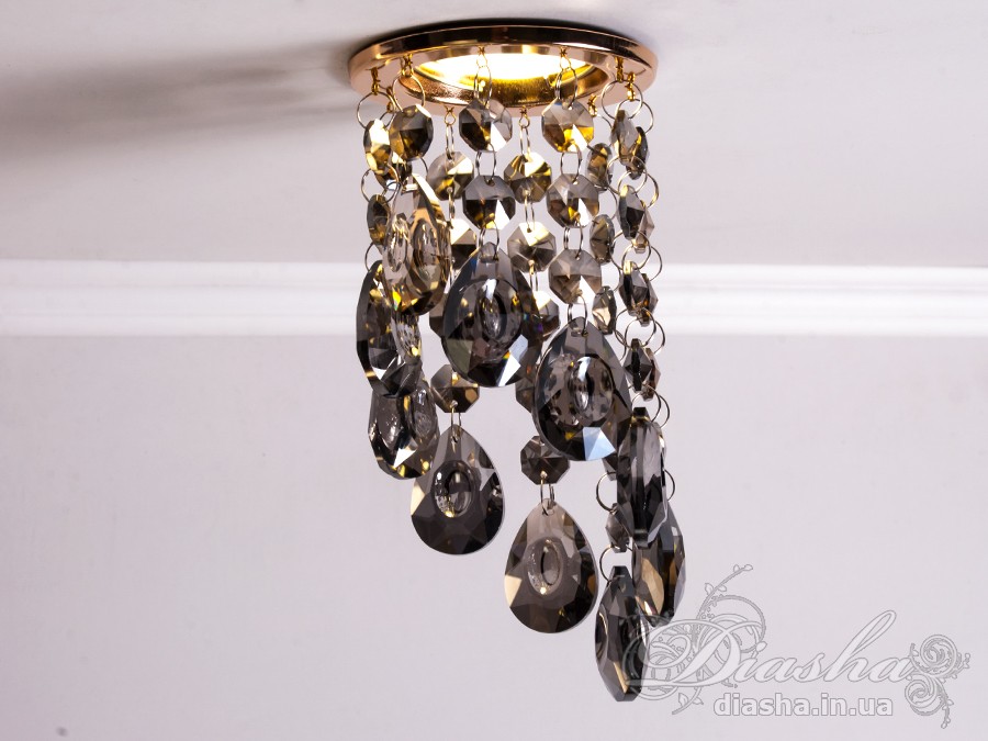 Врізний точковий світильник з кришталевими підвісами являє собою витончене освітлювальне рішення, яке здатне додати розкоші та величі будь-якому простору. Він демонструє багатство інтер'єрних можливостей, відбиваючи найтонші нюанси сучасного дизайну і при цьому підтримуючи класичну естетику.
Центральна частина світильника виконана з міцного металу, фініш якого імітує золото, додаючи елемент розкішного благородства. Від цієї центральної частини спускаються елегантні кришталеві підвіси, кожен з яких є маленьким витвором мистецтва. Криштали мають різноманітні грані, що ловлять світло і переломлюють його в блискучий калейдоскоп, створюючи чарівні ігри світла по всьому приміщенню.
Такий світильник стане чудовим доповненням до інтер'єру залу, де він може бути використаний для створення затишної атмосфери чи служити як основний акцент оформлення. У кухні він може допомогти виділити зону їдальні або підкреслити красу кухонних меблів. В спальні світильник забезпечить м'яке і романтичне освітлення, створюючи ідеальну атмосферу для відпочинку і релаксації.
У просторах кафе та інших громадських місць цей світильник зможе додати нотки ексклюзивності та статусу. Його кришталеві підвіси можуть служити не лише джерелом світла, а й елементом декору, що приваблює погляди і запам'ятовується відвідувачам.
Такий світильник легко можна придбати за доступною ціною, що робить його відмінним вибором для тих, хто прагне купити дешево точковий світильник, але не хоче жертвувати якістю та виглядом. Світильник від ТМ &laquo;Діаша&raquo; поєднує в собі стильність, елегантність та сучасну технологічність, будучи притаманним багатьом стилям від класики до модерну.
Врізний точковий світильник з кришталевими підвісами не просто освітлює простір - він перетворює його, додаючи кожному моменту особливу красу та чарівність, які лише кришталь здатний створити.
