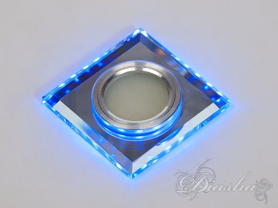 Світлодіодний точковий світильник з вбудованим підсвічуванням є витонченим доповненням до будь-якого інтер'єру, забезпечуючи не лише функціональне освітлення, але й стильний декоративний елемент. Оснащений 3-ватним світлодіодним підсвічуванням з холодним білим світлом температури 6400K, цей світильник здатен створити яскравий акцент або м'яке розсіяне світло, що ідеально підходить для підсвічування робочих поверхонь, ніш або як додаткове освітлення у комбінації з основним джерелом світла.
Конструктивно світильник розділений на дві основні частини: декоративну, яка видно і прикрашає стелю, та функціональну, що прихована в стелі і містить джерело світла. Декоративна частина вражає своєю прозорістю і блиском, надаючи елементу вишуканості і сучасності. Затискачі, що входять до функціональної частини, забезпечують надійне кріплення до підвісної стелі, що робить монтаж простим та зручним.
Завдяки сучасному дизайну та високій функціональності, цей точковий світильник може бути ідеальним рішенням для створення унікального освітлення в будинках, офісах, галереях, а також у комерційних та громадських просторах.
Для оптових покупців цей світильник пропонується упаковками по 50 штук, що зручно для великих проектів освітлення. Лампа MR-16, яка не входить до комплекту, забезпечує легкість вибору та заміни джерела світла залежно від потреб і переваг користувача.