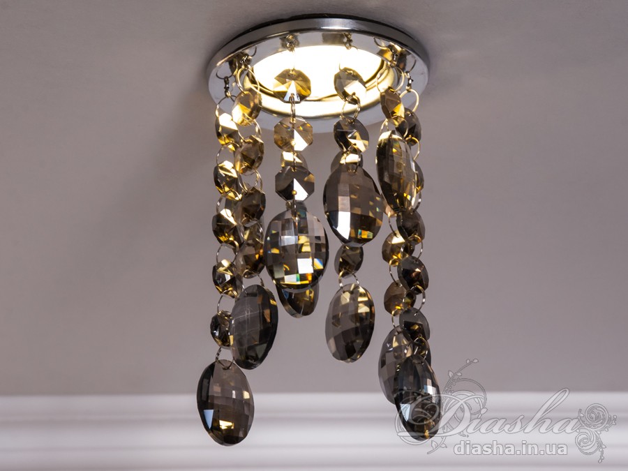 Бездоганна елегантність цього точкового світильника, поєднана з сяючим блиском високоякісного кришталю принесе Вам чимало приємних хвилин.
У центрі його уваги &ndash; кругле світлодіодне точкове джерело, яке ідеально освітлює приміщення. Його основа відзначається чистотою та сучасністю, але справжня витонченість починається по його обрамленню.
Крайові частини світильника прикрашають матовані чорні шестигранні кришталеві підвіси, розташовані по краях. Кожен із них &ndash; окрема скульптурна форма, створюючи чудовий ефект різноманіття та глибини. Кришталеві підвіси по краю світильника створюють геометричний ритм та гармонію.
Ці маленькі шестигранні підвіси слугують не лише декоративним елементом, але й функціональною частиною. Вони створюють градацію висоти, а до їхніх кінців підвішені великі кришталеві краплі, що нагадують про дорогоцінні каплі роси. Такий елементарний, але вишуканий дизайн додає світильнику витонченості та природності.
Різноманітні висоти кришталевих підвісів не лише створюють динаміку в образі, але і розвивають унікальний світловий пейзаж. Кришталі взаємодіють зі світлом, розсіюючи його і створюючи враження м'якої та атмосферної освітленості.
Цей точковий світильник ідеально вписується у сучасні інтер'єри, надаючи приміщенню не лише функціонального, але й художнього значення. Його здатність змінювати динаміку світла та створювати унікальну гру світла виявляється в кожному моменті, роблячи цей світильник як чудовим джерелом освітлення, так і витвором мистецтва, яке надихає та захоплює своєю естетикою.
Наш точковий світильник з кришталевими підвісками ідеально вписується в різноманітні стилі інтер'єру та може бути вдалим доповненням для різних приміщень:
Сучасний стиль (Modern): Своєю сучасною геометричною формою та інноваційним дизайном, світильник виглядає ефектно у сучасних приміщеннях, де важлива чистота ліній та мінімалістичний підхід до декору.
Сучасний класицизм (Modern Classic): Комбінація кришталевих деталей та чорного матового кольору додає елементи класичного стилю, що робить його вдалим вибором для класичних сучасних інтер'єрів.
Лофт (Loft): Чорне покриття та нестандартний дизайн роблять його відмінним вибором для стилізованих лофт-просторів, де важливі нестандартні елементи та сучасна естетика.
Еклектика (Eclectic): Завдяки унікальній формі та різноманіттю висот кришталевих підвісів, світильник може бути вдалою доповнюючою деталлю в інтер'єрах з еклектичним підходом, поєднуючи елементи різних стилів.
Розкіш (Luxury): Кришталеві деталі і високоякісне виконання роблять цей світильник відмінним вибором для розкішних інтер'єрів, де важливо створити враження розкоші та елегантності.
Щодо приміщень, цей світильник може бути впізнаним у:
Вітальнях та гостьових кімнатах: Як центральний акцент в приміщеннях для відпочинку.
Спальнях: Де його естетика може додати атмосфери розкоші та інтимності.
Ресторанах і вестибюлях готелів: Де важливо створити перше враження розкоші.
Офісах та конференц-залах: Де цей світильник може служити як елемент сучасного офісного дизайну.
Сучасних арт-просторах: Де його вишуканий дизайн може виглядати як самостійний об'єкт мистецтва.
Загалом, цей світильник демонструє універсальність та може бути успішно впроваджений в різних стилях та типах приміщень.