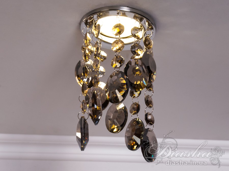 Врізний точковий світильник з кришталевими підвісами являє собою витончене освітлювальне рішення, яке здатне додати розкоші та величі будь-якому простору. Він демонструє багатство інтер'єрних можливостей, відбиваючи найтонші нюанси сучасного дизайну і при цьому підтримуючи класичну естетику.
Центральна частина світильника виконана з міцного металу, фініш якого імітує золото, додаючи елемент розкішного благородства. Від цієї центральної частини спускаються елегантні кришталеві підвіси, кожен з яких є маленьким витвором мистецтва. Криштали мають різноманітні грані, що ловлять світло і переломлюють його в блискучий калейдоскоп, створюючи чарівні ігри світла по всьому приміщенню.
Такий світильник стане чудовим доповненням до інтер'єру залу, де він може бути використаний для створення затишної атмосфери чи служити як основний акцент оформлення. У кухні він може допомогти виділити зону їдальні або підкреслити красу кухонних меблів. В спальні світильник забезпечить м'яке і романтичне освітлення, створюючи ідеальну атмосферу для відпочинку і релаксації.
У просторах кафе та інших громадських місць цей світильник зможе додати нотки ексклюзивності та статусу. Його кришталеві підвіси можуть служити не лише джерелом світла, а й елементом декору, що приваблює погляди і запам'ятовується відвідувачам.
Такий світильник легко можна придбати за доступною ціною, що робить його відмінним вибором для тих, хто прагне купити дешево точковий світильник, але не хоче жертвувати якістю та виглядом. Світильник від ТМ &laquo;Діаша&raquo; поєднує в собі стильність, елегантність та сучасну технологічність, будучи притаманним багатьом стилям від класики до модерну.
Врізний точковий світильник з кришталевими підвісами не просто освітлює простір - він перетворює його, додаючи кожному моменту особливу красу та чарівність, які лише кришталь здатний створити.