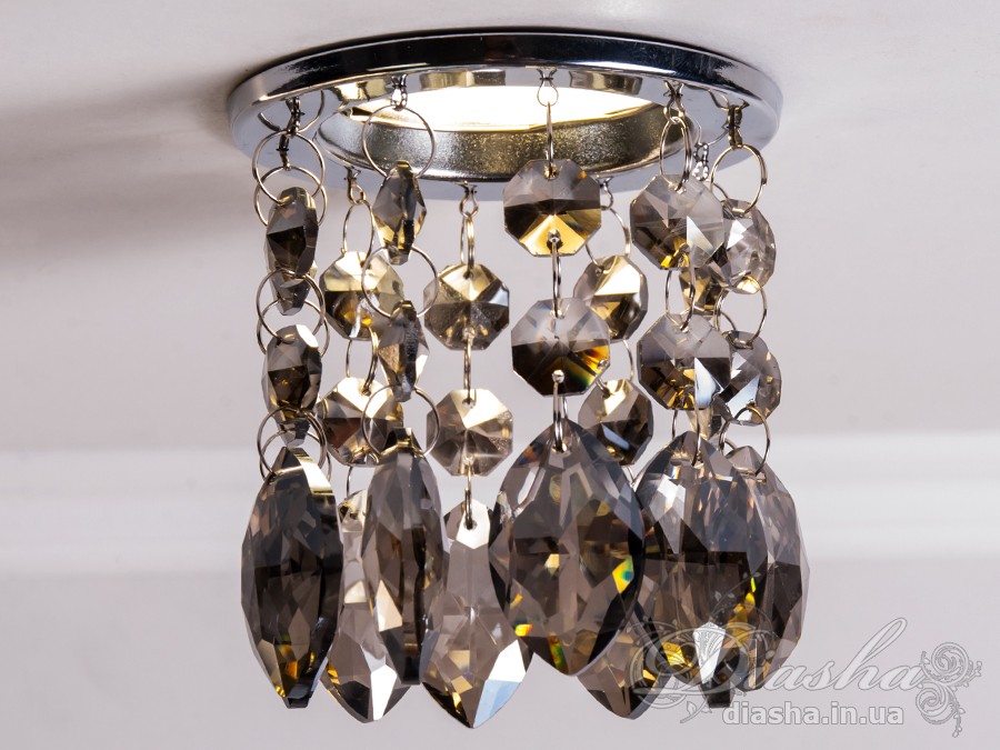 Врізний точковий світильник з кришталевими підвісами являє собою витончене освітлювальне рішення, яке здатне додати розкоші та величі будь-якому простору. Він демонструє багатство інтер'єрних можливостей, відбиваючи найтонші нюанси сучасного дизайну і при цьому підтримуючи класичну естетику.
Центральна частина світильника виконана з міцного металу, фініш якого імітує золото, додаючи елемент розкішного благородства. Від цієї центральної частини спускаються елегантні кришталеві підвіси, кожен з яких є маленьким витвором мистецтва. Криштали мають різноманітні грані, що ловлять світло і переломлюють його в блискучий калейдоскоп, створюючи чарівні ігри світла по всьому приміщенню.
Такий світильник стане чудовим доповненням до інтер'єру залу, де він може бути використаний для створення затишної атмосфери чи служити як основний акцент оформлення. У кухні він може допомогти виділити зону їдальні або підкреслити красу кухонних меблів. В спальні світильник забезпечить м'яке і романтичне освітлення, створюючи ідеальну атмосферу для відпочинку і релаксації.
У просторах кафе та інших громадських місць цей світильник зможе додати нотки ексклюзивності та статусу. Його кришталеві підвіси можуть служити не лише джерелом світла, а й елементом декору, що приваблює погляди і запам'ятовується відвідувачам.
Такий світильник легко можна придбати за доступною ціною, що робить його відмінним вибором для тих, хто прагне купити дешево точковий світильник, але не хоче жертвувати якістю та виглядом. Світильник від ТМ &laquo;Діаша&raquo; поєднує в собі стильність, елегантність та сучасну технологічність, будучи притаманним багатьом стилям від класики до модерну.
Врізний точковий світильник з кришталевими підвісами не просто освітлює простір - він перетворює його, додаючи кожному моменту особливу красу та чарівність, які лише кришталь здатний створити.