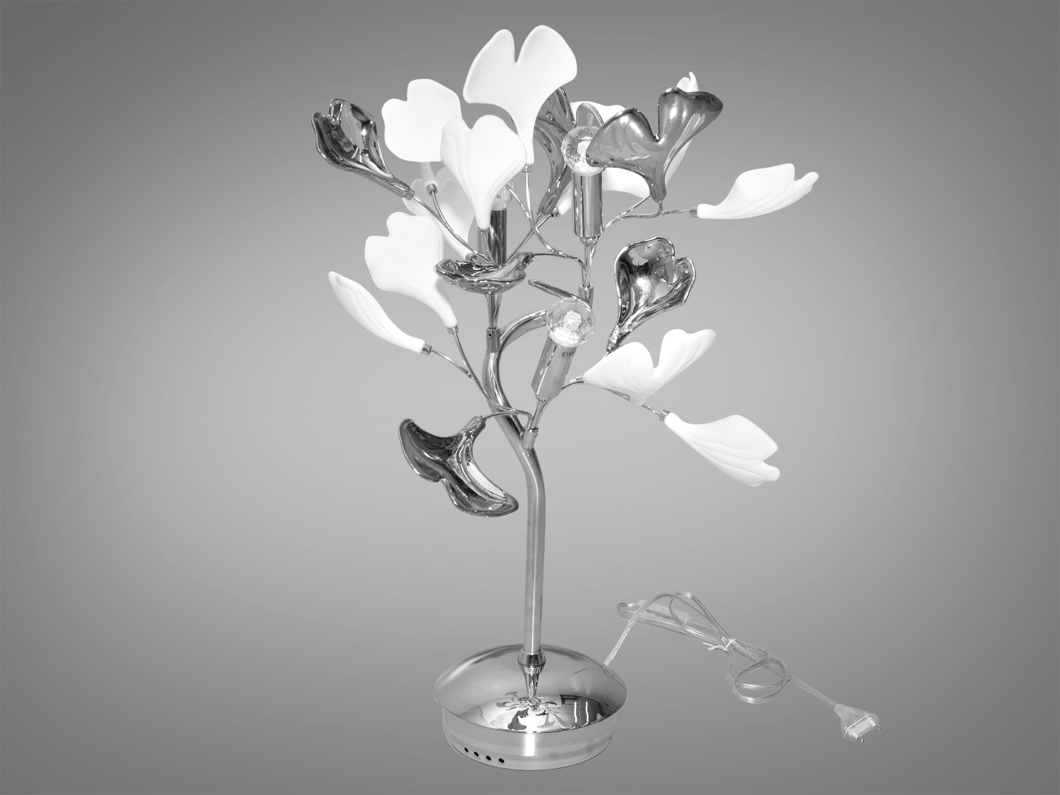 Настільна лампа з фарфоровими елементами втілює в собі поєднання античної витонченості та сучасної практичності, що ідеально вписується в простір для створення гармонійного та затишного освітлення вашого будинку або як декор. Виконує практичну роль, але служить стильним аксесуаром, який допоможе підкреслити вишуканість та унікальність інтер'єру.
Настільна лампа під звичайні лампочки розжарювання, економки або світлодіодні лампи з цоколем Е14, що забезпечує м'яке, але яскраве світло для роботи або відпочинку.
Серце лампи &ndash; це надійний металевий каркас, на якому елегантно розташовані керамічні пелюстки у формі листя гінкго білоба.Пелюстки, виконані в техніці глазурі під металік у золотих або хромованих варіантах, вносять у дизайн сучасний вимір, додавши нотки розкоші та блиску. Компактна форма лампи дозволяє їй легко вписатися в будь-яке дизайнерське рішення, офісний стіл або кут для читання в домашній бібліотеці.
Лампа до комплекту не входить.