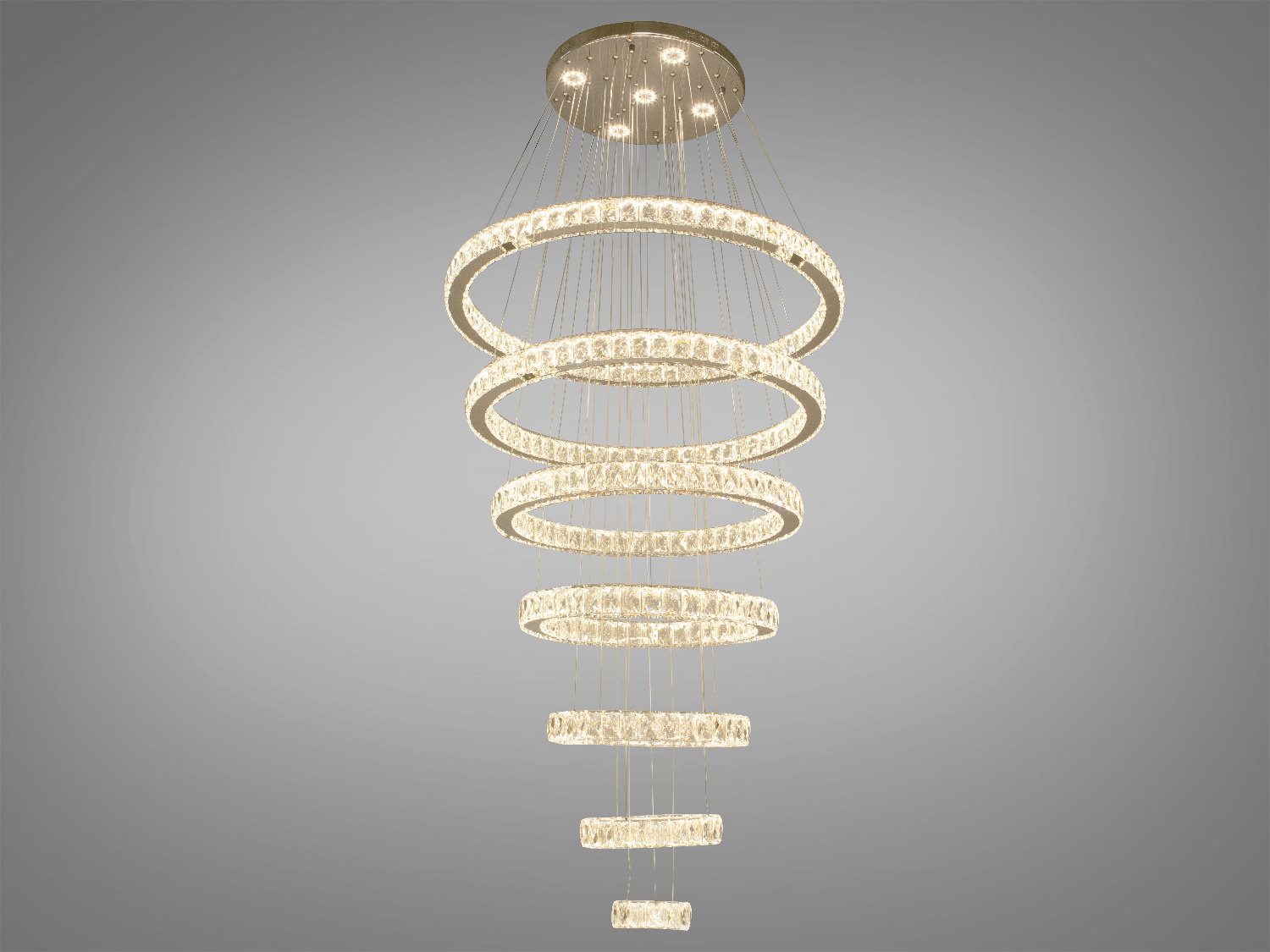 Кришталева каскадна LED люстра-підвіс для холу також ідеально підходить для використання в холах або вітальні, сходових зонах приватних будинків, ресторанів або готелях, люксових спальнях, балконах або у вестибюлі, бізнес-центри або офісні простори.
Загальна концепція люстри робить її універсальною та здатною доповнювати різноманітні стилі інтер'єру, таких як: класичний стиль, сучасний мінімалізм, еклектика, ретро чи вінтаж, люксовий модерн, бароко чи рококо.
Каскадні люстри ідеально підійдуть для використання у приміщеннях з висотою від двох з половиною до п'яти, і навіть до семи метрів.
Починаючи з верхнього кришталевого кільця, що граційно спускається вниз, кожне наступне кільце вражає своєю елегантністю та пропорційністю. Рівновіддалені кільця, які послідовно зменшуються, створюють враження легкості та гармонії.
Основа кришталевого кільця виготовлена з високоякісного металу, який не тільки забезпечує стійкість та надійність, але й служить чудовою основою для блиску кристалів.
Функціональною особливістю цієї люстри є наявність пульта дистанційного керування, що дозволяє регулювати колірну температуру світла, створюючи різні атмосфери у приміщенні залежно від ваших потреб та настрою.
Кріпиться до стелі будь-якого типу універсальним кріпленням на монтажну планку.