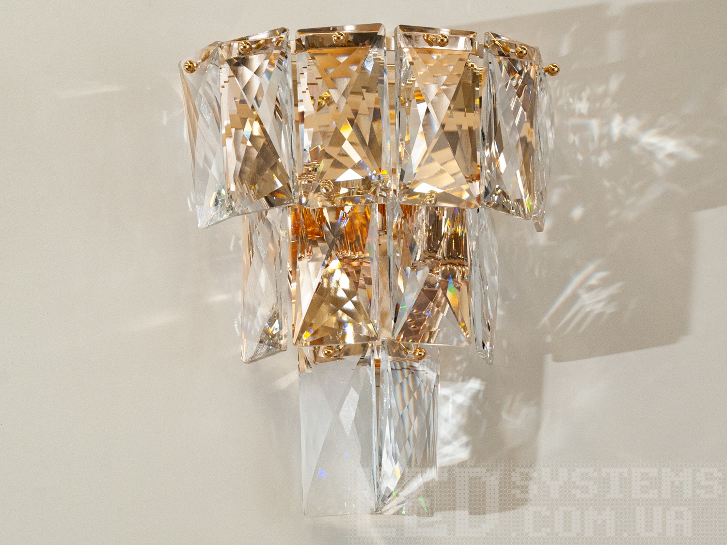 Класичне настінне бра з кришталевими підвісами виконані в класичному стилі і розраховані на 3 лампи: звичайні розжарювання, економки, або світлодіодні лампи з цоколем Е14. Розкішний класичний світильник буде незмінно актуальний як в класичному інтер'єрі, так і в квартирі студії в стилі лофт подарує крапельку строгості і впорядкованості. Кріпиться до стіни, до гіпсокартону або до інших настінним поверхонь.