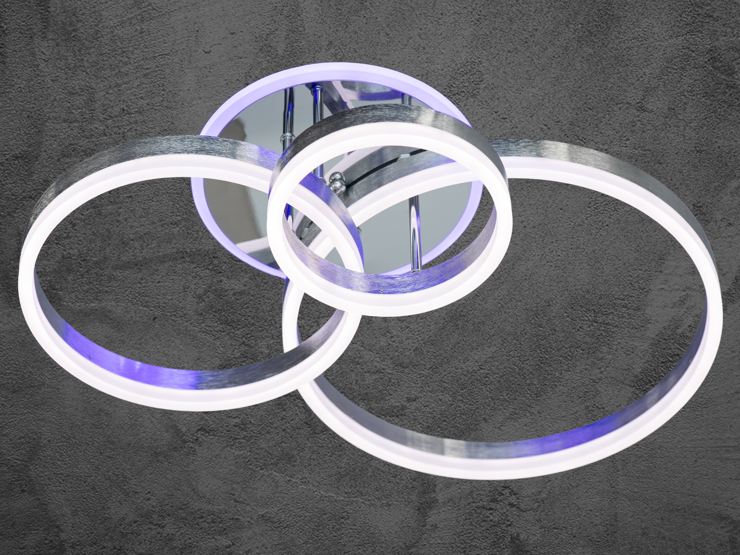 Стельова LED-люстра&nbsp;з підсвіткою, з пультом, з димером підходить на площу приміщення приблизно 18 кв. м. Підходить також для віталень, для залів, спалень і холів, у дитячу кімнату, оскільки немає елементів, що б'ються, створюючи м'яке та рівномірне освітлення з можливістю індивідуального настроювання.
Ця світлодіодна люстра має сучасний і мінімалістичний дизайн, який надасть стильного вигляду будь-якій кімнаті. Вона зроблена у формі перетинних кілець, які створюють ефект об'ємності та глибини, додаючи елегантності в простір. Кільця світяться м'яким, рівномірним світлом, а вбудований димер дає змогу регулювати яскравість, створюючи комфортне освітлення для різних ситуацій &mdash; від яскравого світла для роботи до м'якого приглушеного світла для розслаблювальної атмосфери.
Переваги акрилових розсіювачів знаходять своє вираження в міцності, довговічності та легкості конструкції люстри. Вона вирізняється низьким енергоспоживанням, що робить її економічно вигідною, а також малою висотою від стелі, ідеальною для просторів з обмеженою висотою стелі.
Світлодіодна люстра має кілька режимів: холодний 6000К, нейтральний 4100К, теплий 3200К, кольорова підсвітка, поєднаний режим &mdash; будь-яке основне світло плюс будь-який колір світлодіодної підсвітки. Регулювання яскравості люстри від 5 до 100% здійснюється за допомогою пульта дистанційного керування, що входить до комплекту.
Світильник легко монтується на будь-які типи стель завдяки універсальному кріпленню на монтажну планку, що робить встановлення швидким, зручним і надійним.
Плюсами люстри є багатофункціональність: кілька режимів освітлення й кольорова підсвітка, регульована яскравість за допомогою димера, легкість встановлення на будь-які типи стель.