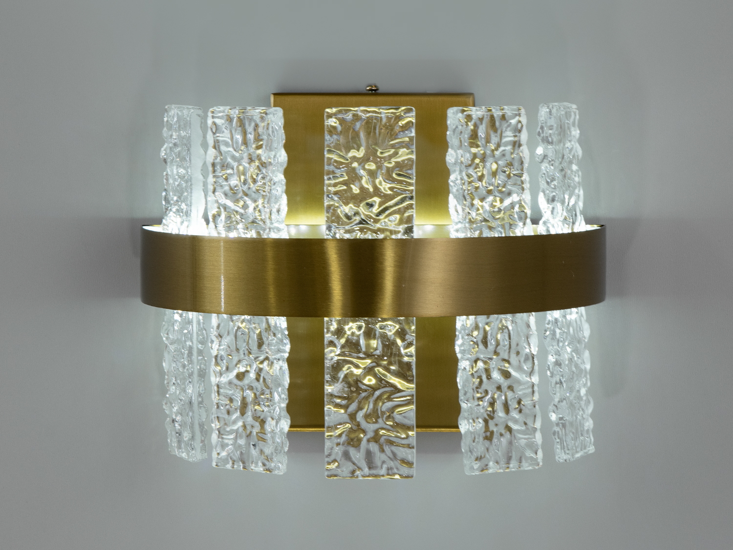 Світлодіодний настінний світильник для залу з потужністю 18Вт видає достатньо світла, щоб бути самодостатнім джерелом підсвічування, дозволяє м'яко підсвітити простір, створюючи почуття тепла і затишку, необхідне для вечірнього релаксу.
За допомогою вимикача можна змінювати колірну температуру світильника: теплий 3200&deg;К, нейтральний 4100&deg;К, холодний 6000&deg;К. Колірна температура перемикається простим вимкненням-вмиканням світильника.
Функціональність світильника доповнюється його стильним зовнішнім виглядом, де кожна деталь продумана до дрібниць, золотий колір каркасу поєднується з прозорістю підвісів, створюючи відчуття розкішної легкості та елегантності.
Кріпиться до настінних поверхонь будь-якого типу універсальним кріпленням на монтажну планку.