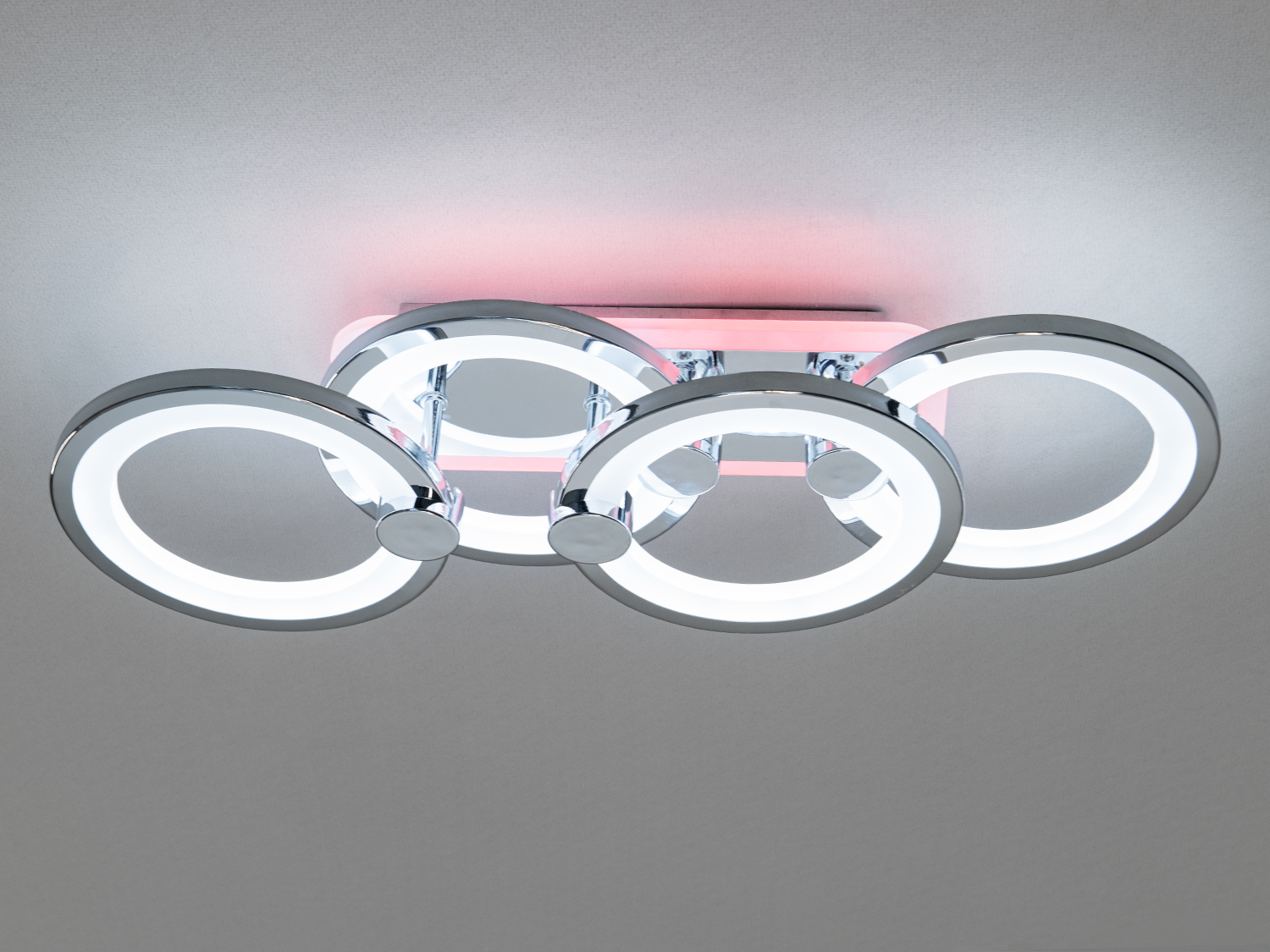 Подовжена LED люстра на кухню з підсвічуванням — це сміливе та елегантне рішення для тих, хто цінує геометрію, симетрію та візуальну чистоту. Чотири кільця, переплетені між собою в плавній лінії, формують цільну композицію, що нагадує динаміку руху або стилізовану нескінченність.