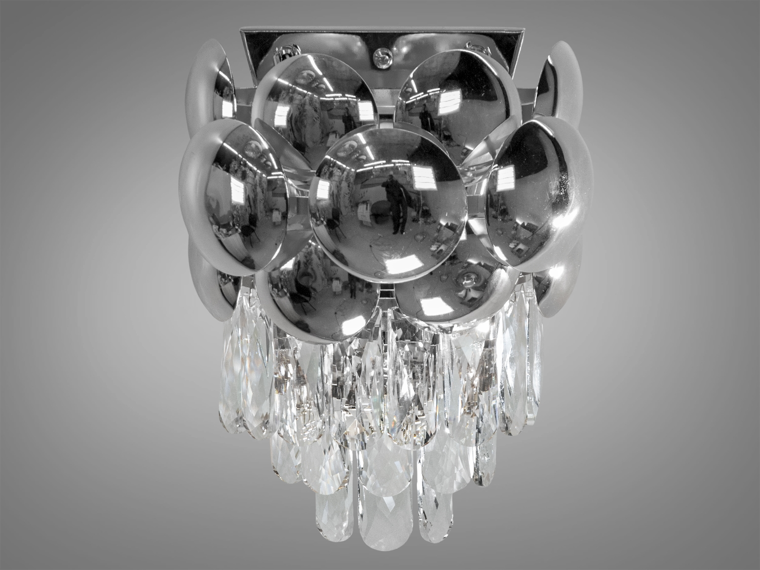 Вишуканий класичний кришталевий світильник у вітальню може бути використаний як окремий акцент створюючи гармонійне світлове середовище у вашому будинку. Він ідеально підійде як класичних інтер'єрів з розкішними деталями, так сучасних просторів, де шукають елементи дизайну з характером.
Використовуються високоякісні матеріали метал та кришталь. Світильник застосовується для сучасного стильного інтер'єру. У класичний інтер'єр вони вносять нотки сучасності, а квартирі студії в стилі лофт дарують крапельку суворості та впорядкованості. Нові настінні світильники виконані в класичному стилі та розраховані на 2 лампи з цоколем Е14.
З його металевою основою, блискучою як дзеркало, та рядами прозорих кришталів, світильник випромінює мерехтливе та іскрите світло, створюючи атмосферу елегантності та святковості. Кристали різного розміру, розташовані навколо лампочок цоколь Е14, немов танцюють у ритмі відблисків та променів, що виходять з їхнього центру.
Лампи до комплекту не входять.